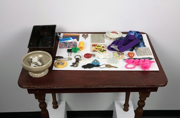 Jessica Pauls b. 1973 and Digno Vibat b. 1946, "Comfort to the touch", photograph, keepsakes, table, paper, 2023.